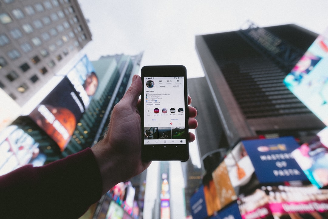 high angle photo of person holding turned on smartphone with tall buildings background - Instagram, tags: integrate - unsplash