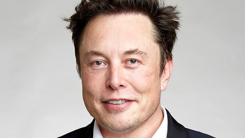 Elon Musk - An image of Musk smiling in a suit, sans tie, tags: mutant july - CC BY-SA